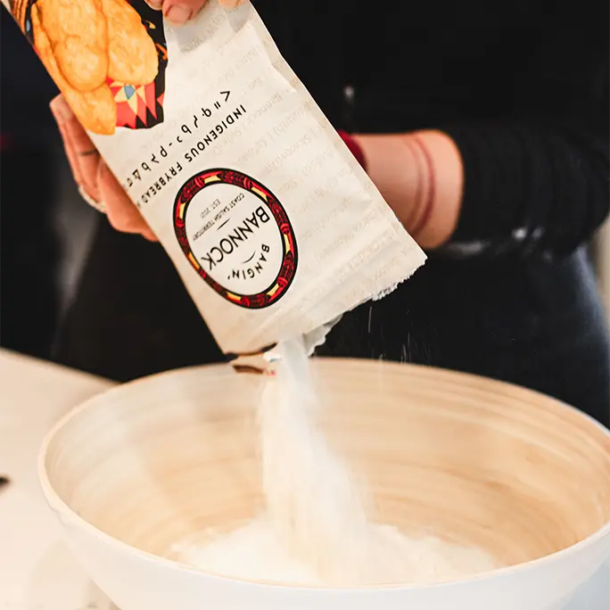 A woman pouring Bangin' Bannock mix into a bowl. 