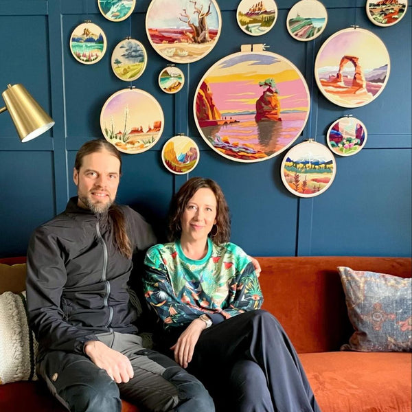 Two people sitting on a couch in a room with decorative wall art.