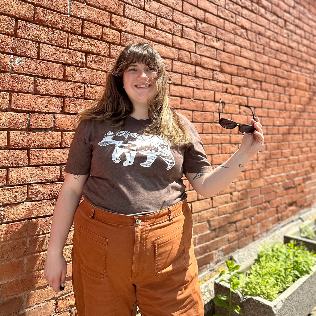 Emily stands in the sun wearing Roaming Bear t-shirt in brown.