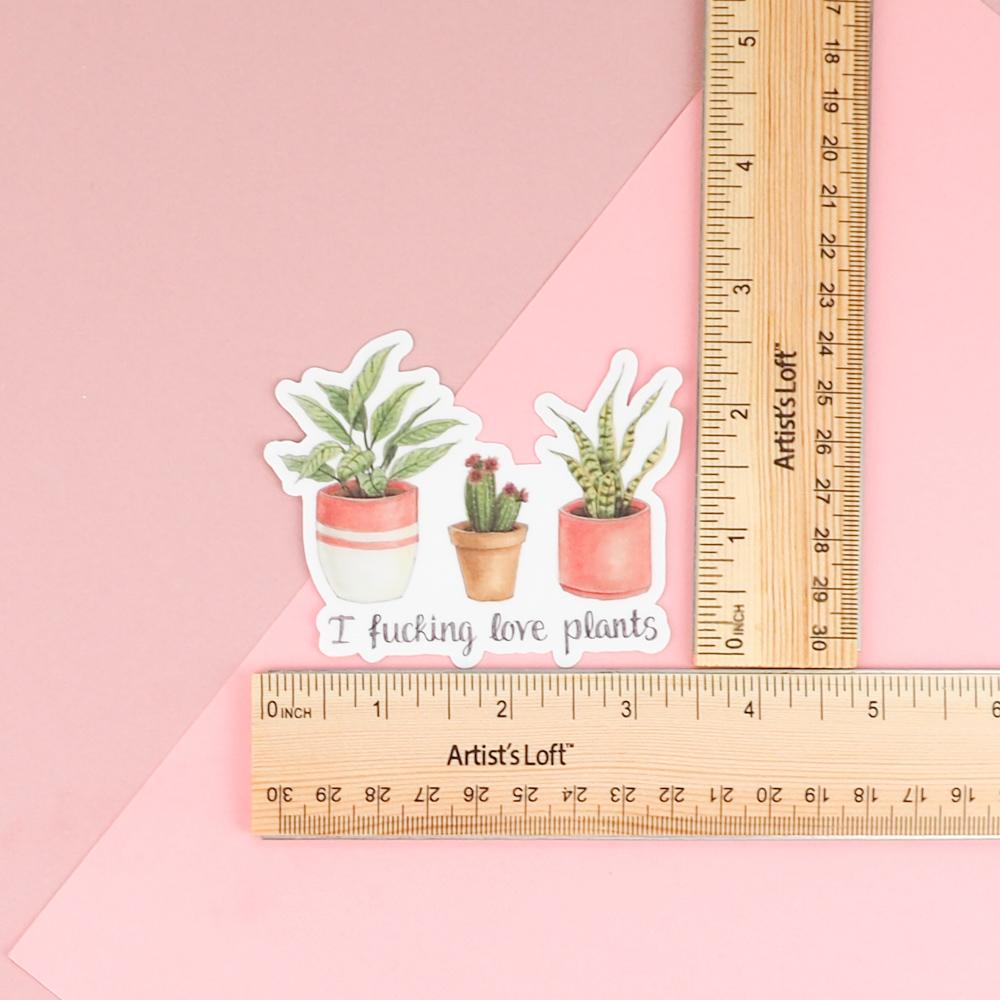 A sticker featuring artwork of a tropical plant, a cactus and a succulent (each in it's own cute pot) with the words "I fucking love plants" under them.