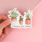 A sticker featuring artwork of a tropical plant, a cactus and a succulent (each in it's own cute pot) with the words "I fucking love plants" under them.