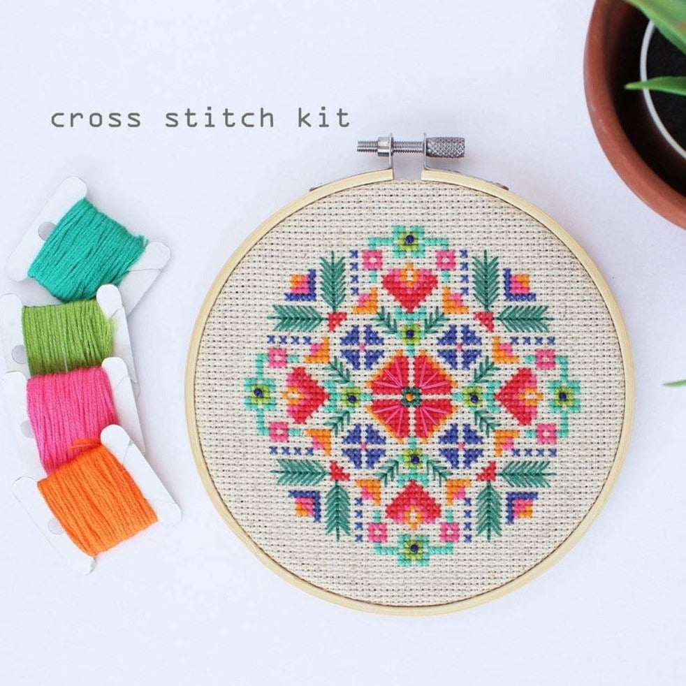 Cross stitch pattern that looks like flowers in red, orange, green, blue, and pink.