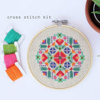 Cross stitch pattern that looks like flowers in red, orange, green, blue, and pink.